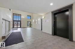 Spacious common area featuring large format tile flooring, a prominent elevator, and a wall of individual mailboxes - 