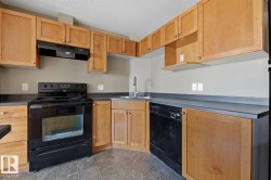 Functional kitchen featuring wood-finish cabinetry, dark countertops, and tile flooring - 