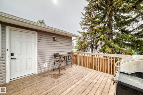 Spacious outdoor deck featuring wood flooring, a light gray siding exterior, and a white panel door - 3802 52 Street, Wetaskiwin, AB 