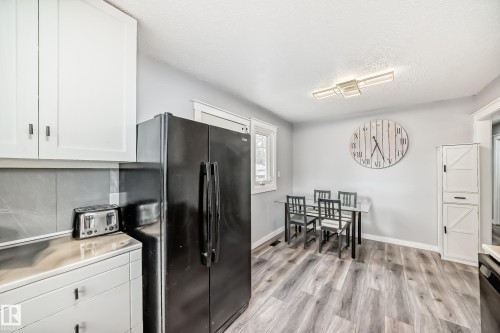 Kitchen area featuring white cabinetry, gray backsplash, and wood-finish flooring - 3802 52 Street, Wetaskiwin, AB 