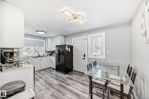 Bright kitchen featuring white cabinetry, wood-finish flooring, a contemporary ceiling light fixture, and a window above the sink - 3802 52 Street, Wetaskiwin, AB 