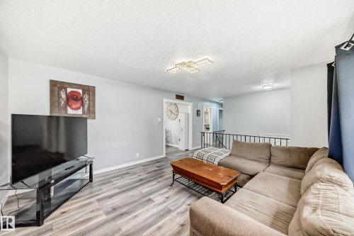 Living area featuring light gray walls, wood-finish flooring, and a modern ceiling light fixture - 3802 52 Street, Wetaskiwin, AB 