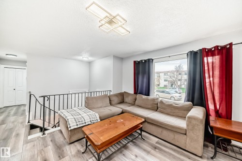 Living area featuring wood-finish flooring and a contemporary overhead light fixture - 3802 52 Street, Wetaskiwin, AB 