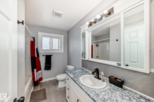 Bathroom featuring a spacious vanity with an oval undermount sink, a gray patterned countertop, and a matte black single-handle faucet - 3802 52 Street, Wetaskiwin, AB 