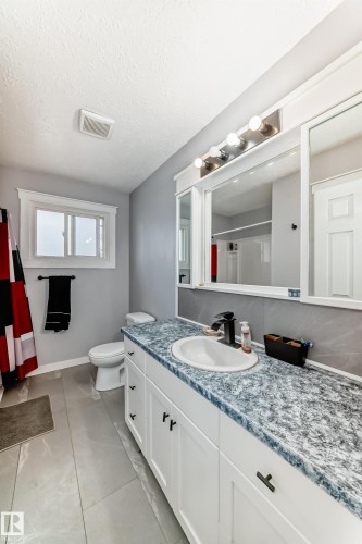 White vanity with a granite-look countertop, integrated sink, and matte black faucet - 3802 52 Street, Wetaskiwin, AB 