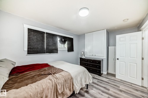 Bedroom featuring light gray walls, wood-finish flooring, a window with blinds, and built-in white cabinetry - 3802 52 Street, Wetaskiwin, AB 