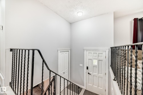 Entryway featuring a decorative white door with window pane, iron baluster railing, and recessed ceiling lighting - 3802 52 Street, Wetaskiwin, AB 