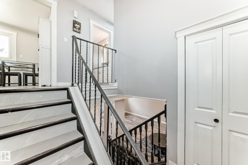 Staircase featuring dark wood-finish treads and risers with a wrought iron railing - 3802 52 Street, Wetaskiwin, AB 