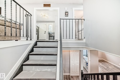 Multi-level interior featuring a staircase with wrought iron railings and wood-finish flooring - 3802 52 Street, Wetaskiwin, AB 