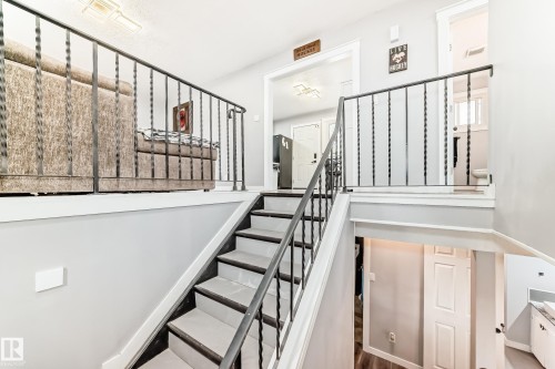 Split-level interior featuring a staircase with wrought iron railings and wood-finish treads - 3802 52 Street, Wetaskiwin, AB 