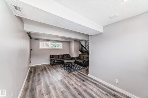 Spacious lower-level area with wood-finish flooring, recessed lighting, and a window - 3802 52 Street, Wetaskiwin, AB 