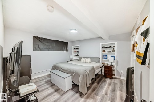 Bedroom featuring light gray walls, wood-finish flooring, and built-in shelving - 3802 52 Street, Wetaskiwin, AB 