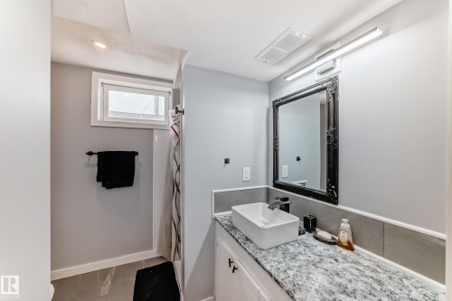 Bathroom featuring a contemporary vessel sink, white vanity cabinetry, and a patterned stone-finish countertop - 3802 52 Street, Wetaskiwin, AB 