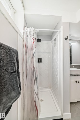 White shower stall featuring a diamond-patterned wall texture and a black rain showerhead - 3802 52 Street, Wetaskiwin, AB 