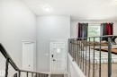 Multi-level interior featuring a decorative wrought iron railing, vaulted ceiling, and a paneled entry door with frosted glass insert - 3802 52 Street, Wetaskiwin, AB 
