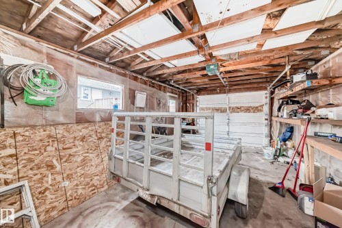 Interior garage space featuring exposed wooden ceiling beams and unfinished oriented strand board walls - 3802 52 Street, Wetaskiwin, AB 