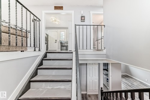 Multi-level interior featuring a staircase with dark wood-finish treads and light-toned risers, complemented by black wrought iron railings - 3802 52 Street, Wetaskiwin, AB 