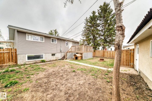 Spacious backyard featuring a wooden privacy fence, a raised wood deck with lattice skirting, and a concrete paver pathway - 3802 52 Street, Wetaskiwin, AB 