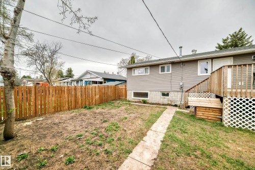 Backyard featuring a privacy fence, a wooden deck with lattice skirting, and a concrete paver walkway - 3802 52 Street, Wetaskiwin, AB 