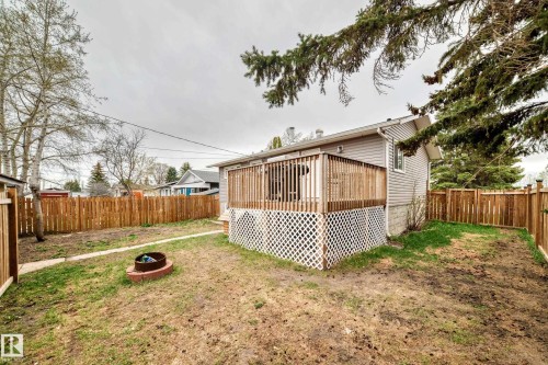 Rear exterior featuring a wood deck with lattice skirting, wood fencing, and a fire pit - 3802 52 Street, Wetaskiwin, AB 