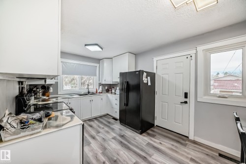 Kitchen featuring white cabinetry, wood-finish flooring, and a corner sink with a window above - 3802 52 Street, Wetaskiwin, AB 