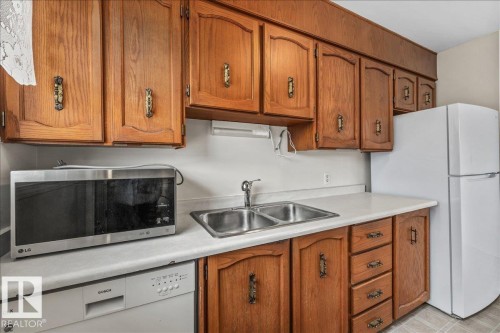 Kitchen featuring wood cabinetry, a double basin stainless steel sink, and light countertops - 24 Elizabeth Drive, Fort Saskatchewan, AB - Indoor Photo Showing Kitchen With Double Sink