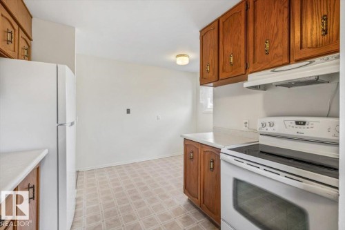 Kitchen featuring wood cabinetry, white countertops, built-in range, and a white refrigerator - 24 Elizabeth Drive, Fort Saskatchewan, AB - Indoor Photo Showing Kitchen