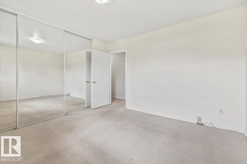 Bedroom featuring wall-to-wall carpeting, light-toned wall finishes, and a mirrored wardrobe with sliding doors - 24 Elizabeth Drive, Fort Saskatchewan, AB - Indoor Photo Showing Other Room