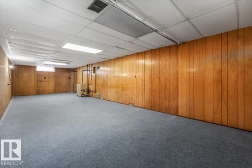 Spacious room featuring wood paneling, drop ceiling, and gray carpeting - 24 Elizabeth Drive, Fort Saskatchewan, AB - Indoor Photo Showing Basement
