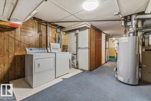 Utility room featuring laundry appliances, a water heater, and paneled walls - 24 Elizabeth Drive, Fort Saskatchewan, AB - Indoor Photo Showing Laundry Room