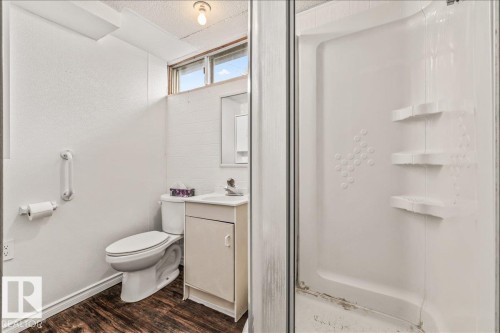 Compact bathroom featuring a stand-up shower with integrated shelving, a single vanity with storage, and wood-finish flooring - 24 Elizabeth Drive, Fort Saskatchewan, AB - Indoor Photo Showing Bathroom