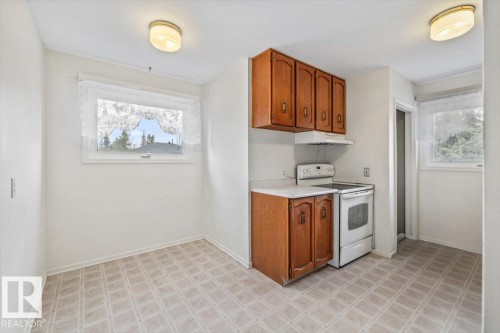 Functional kitchen space featuring wood-finish cabinetry, white countertop, and integrated appliances including a range and range hood - 24 Elizabeth Drive, Fort Saskatchewan, AB - Indoor Photo Showing Kitchen