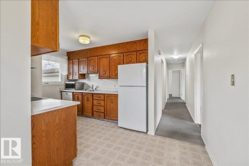 Kitchen featuring wood-finish cabinetry, light-toned countertops, and a double basin sink - 24 Elizabeth Drive, Fort Saskatchewan, AB - Indoor Photo Showing Kitchen