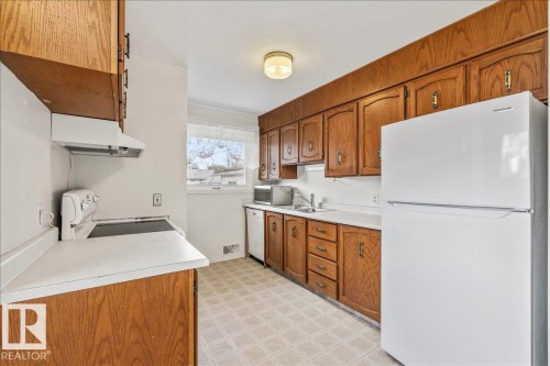 Kitchen featuring wood cabinetry, white countertops, built-in range hood, and a window with natural light - 24 Elizabeth Drive, Fort Saskatchewan, AB - Indoor Photo Showing Kitchen With Double Sink