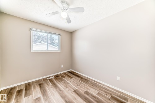 This room features wood-look flooring, neutral wall paint, and a window providing natural light - 10329 150 Street, Edmonton, AB - Indoor Photo Showing Other Room