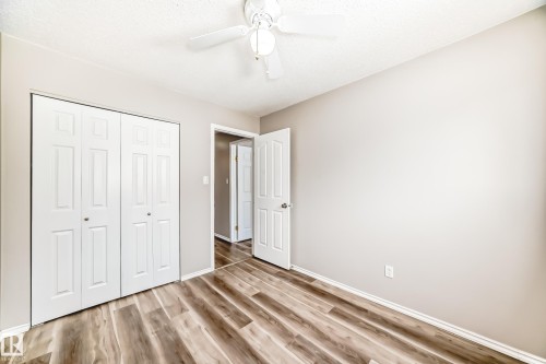 This room features wood-look flooring, light-colored walls, a ceiling fan, and white bi-fold closet doors - 10329 150 Street, Edmonton, AB - Indoor Photo Showing Other Room