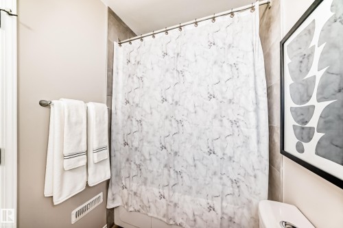 Bathroom featuring light-toned walls, a shower with a patterned curtain, and tiled shower walls - 10329 150 Street, Edmonton, AB - Indoor Photo Showing Bathroom
