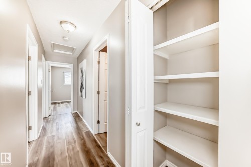 The hallway features wood-look flooring and includes an integrated storage closet with shelving - 10329 150 Street, Edmonton, AB - Indoor
