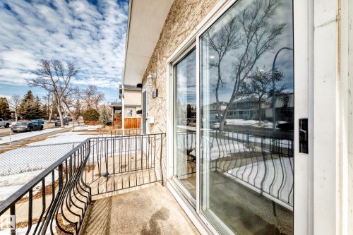 The property features a private balcony with a wrought iron railing, an exterior wall with textured siding, and a large sliding glass door - 10329 150 Street, Edmonton, AB - Outdoor