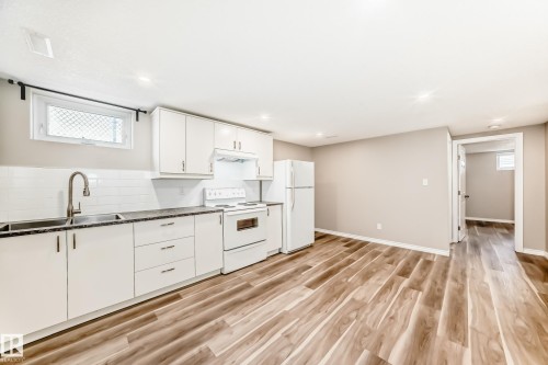 The kitchen features white cabinetry, a white subway tile backsplash, and a double basin stainless steel sink with a gooseneck faucet - 10329 150 Street, Edmonton, AB - Indoor Photo Showing Kitchen