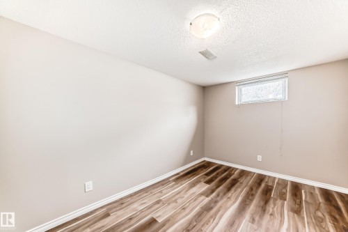 This room features wood-style flooring, light-toned walls, and a ceiling-mounted light fixture - 10329 150 Street, Edmonton, AB - Indoor Photo Showing Other Room