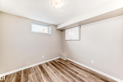 This room features wood-look flooring, a window providing natural light, and a built-in cabinet for storage - 10329 150 Street, Edmonton, AB - Indoor Photo Showing Other Room