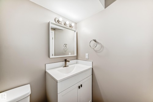 The bathroom features a modern vanity with a white countertop and a rectangular sink, complemented by a brushed nickel faucet - 10329 150 Street, Edmonton, AB - Indoor Photo Showing Bathroom