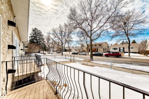 The property features a balcony with black metal railings, offering a view of the street with other properties and bare trees - 10329 150 Street, Edmonton, AB - Outdoor