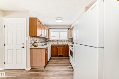The kitchen features wood cabinetry, a tiled backsplash, and a window above the sink - 10329 150 Street, Edmonton, AB - Indoor Photo Showing Kitchen With Double Sink
