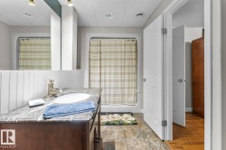 Bathroom featuring a dark wood vanity with a marbled countertop, an undermount sink, and a brushed nickel faucet - 
