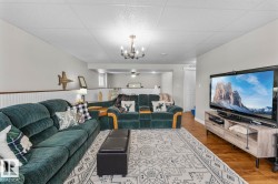 Living area featuring wood-finish flooring, drop ceiling with recessed lighting, and wainscoting - 