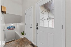 Entryway featuring a white paneled door with decorative glass inserts, a secondary paneled door, and textured tile flooring - 