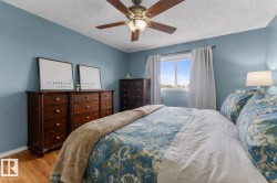 Bedroom featuring a ceiling fan with integrated lighting, a window with natural light, wood-finish flooring, and blue painted walls - 