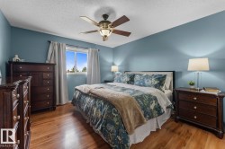 Bedroom featuring wood-finish flooring, a ceiling fan with integrated lighting, and a window with white trim - 